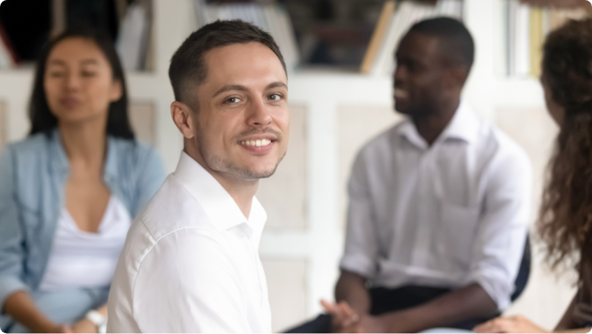 Man smiling with people blurred behind him