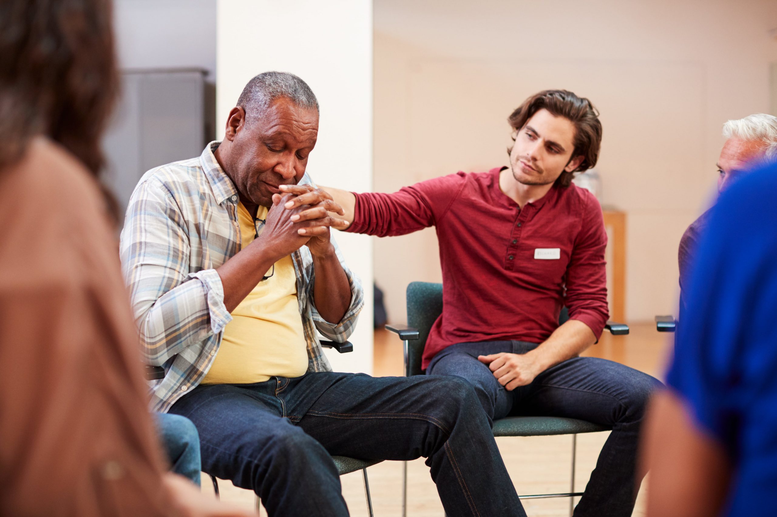 Man comforting another man in group therapy